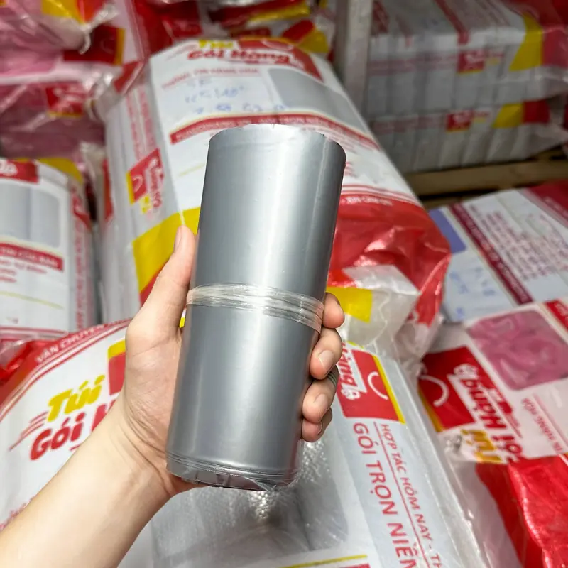 Cuộn túi niêm phong màu bạc plus cầm trên tay, chụp tại kho Túi Gói Hàng VN