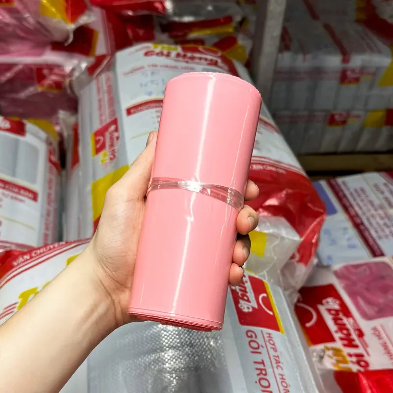 Cuộn túi niêm phong màu hồng pastel cầm trên tay, chụp tại kho Túi Gói Hàng VN