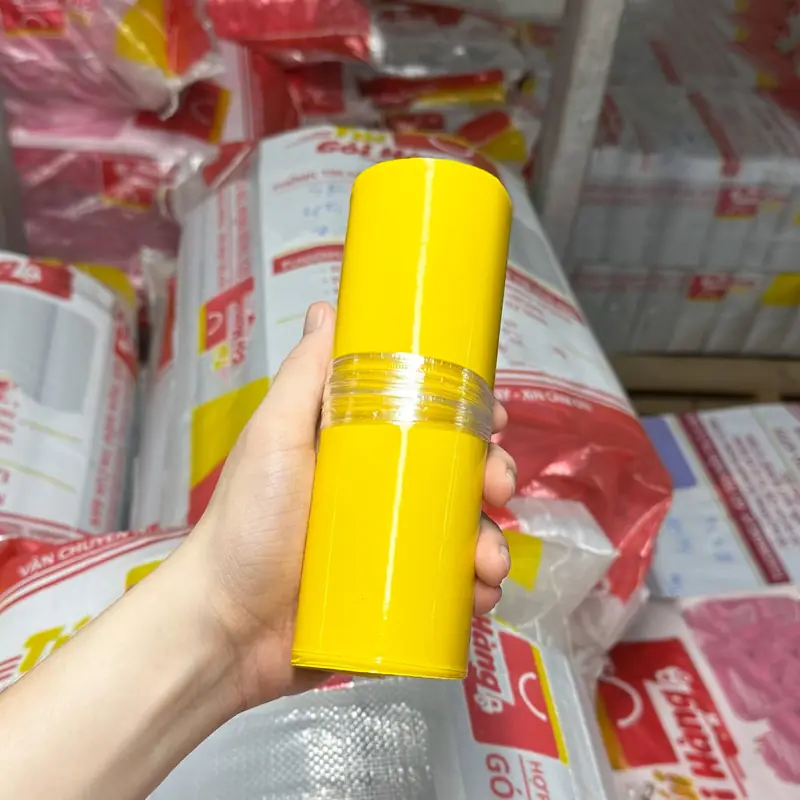 Cuộn túi niêm phong màu vàng cầm trên tay, chụp tại kho Túi Gói Hàng VN