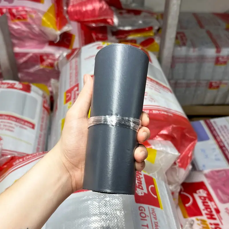 Cuộn túi niêm phong màu xám đen cầm trên tay, chụp tại kho Túi Gói Hàng VN