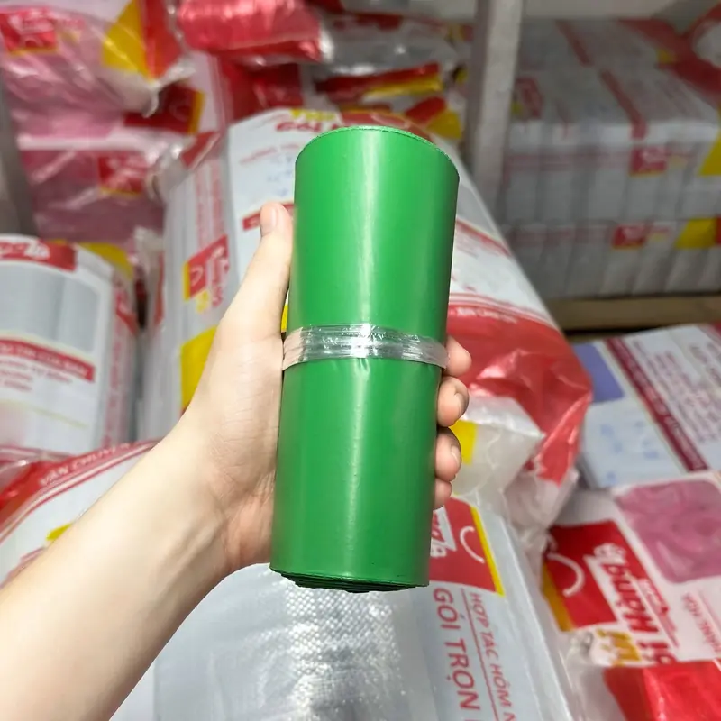 Cuộn túi niêm phong màu xanh lá cầm trên tay, chụp tại kho Túi Gói Hàng VN